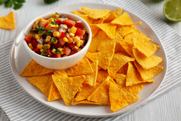 Homemade Corn Salsa with Tortilla Chips on a Plate, side view.