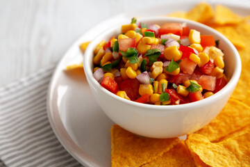 Homemade Corn Salsa with Tortilla Chips on a Plate, low angle view. Close-up.