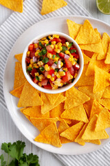 Homemade Corn Salsa with Tortilla Chips on a Plate, top view. Overhead, from above, flat lay.