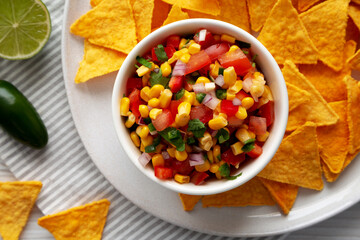 Homemade Corn Salsa with Tortilla Chips on a Plate, top view. Overhead, from above, flat lay. Close-up.