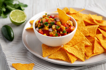 Homemade Corn Salsa with Tortilla Chips on a Plate, side view.