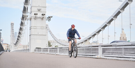 Man riding on bicycle across the bridge in the city.