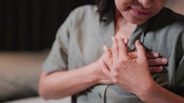 Woman feels pain when touching her chest, has a heart attack and is worried, suffers from myocardial infarction or heart disease. Woman