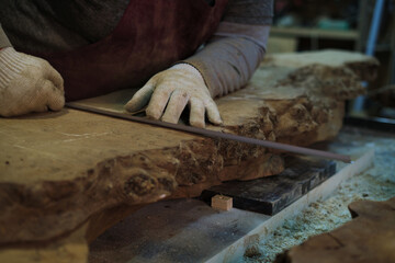 Gloved hands measure timber, a crucial step. It reflects the meticulous nature of sustainable wood sourcing.