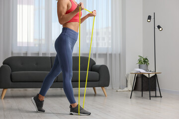 Woman doing exercise with fitness elastic band at home, closeup