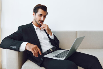 Man working notebook sofa office sitting freelance laptop job video call suit using businessman