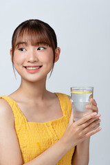 Vitamin Shot. Attractive asian woman drinking mineral water with lemon from glass