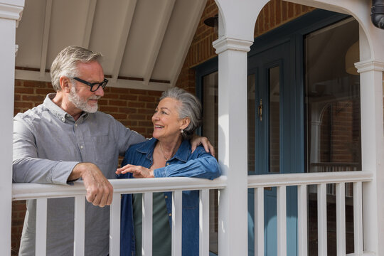 Happy senior couple standing in porch smiling together