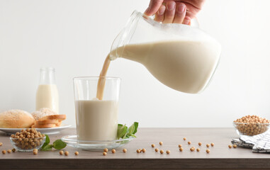 Filling glass with soy milk from a jug white isolated