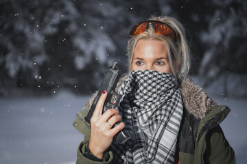 Girl shooter with a pistol in cold winter evening.