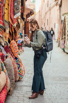 Female tourist taking photos of cushions at market