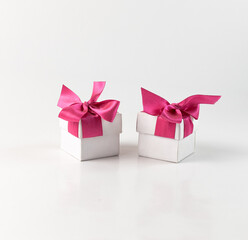 Две маленькие белые коробочки с красными бантами