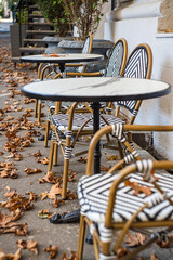 Street cafe tables covered with fallen leaves