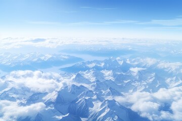  an aerial view of a mountain range with clouds in the foreground and a bright blue sky in the background.