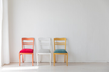Fototapeta na wymiar Three colorful vintage chairs in white room interior