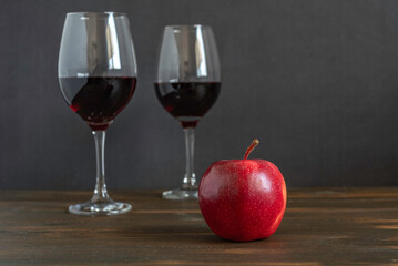 Fresh apple for Jewish holiday Rosh Hashanah on the background of red wine and dark wood.
