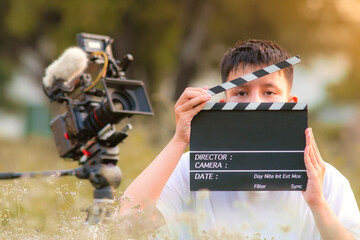 Teenage boy holding a film slate or film clapper board in the movie industry. new content creator, young director.