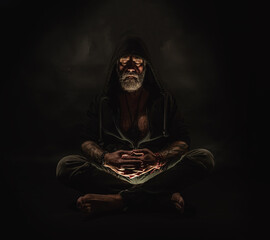 meditating man in a hood sits on the ground, man on the hands of the tattoo, atelier photos, black background. - obrazy, fototapety, plakaty