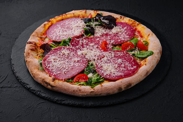 Delicious pizza with salami, arugula and tomatoes