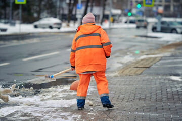 Worker throw snow from sidewalk on road. Worker throwing snow, clearing footpath. Worker cleaning...