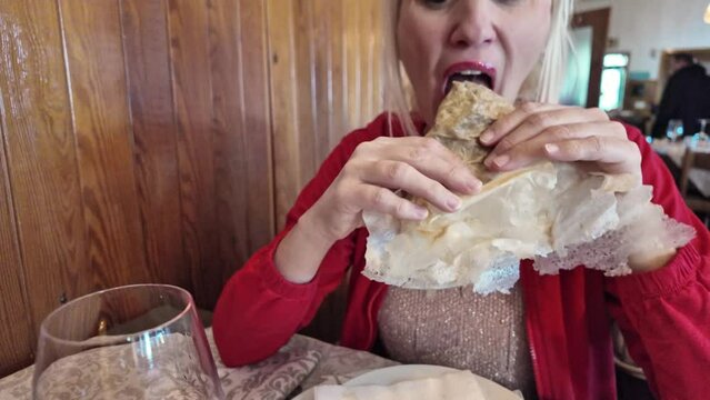 SLOW MOTION: A lady relishing a Borlengo, a tasty dish from Italy's Emilia-Romagna region. Bursting with meat and cheese, this traditional delight is a local favorite in Modena and Bologna.