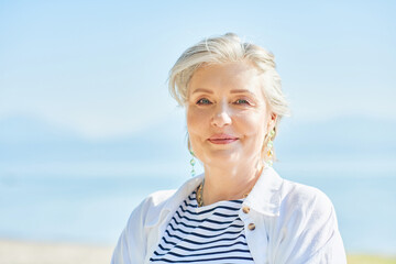 Outdoor summer closeup portrait of happy and healthy mature 50 - 55 year old woman enjoying nice sunny day by the lake or sea, active lifestyle - obrazy, fototapety, plakaty