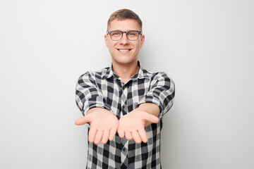 Handsome man in glasses holding something in hand, demonstrating empty space for product or text...