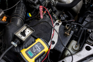 Fototapeta premium Engine engineer is recharging car battery because car battery is depleted. concept car maintenance.