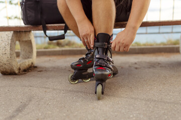 Legs of young man putting on roller skates in the park