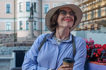 A girl drinks coffee from a paper cup in a coffee shop on the street of an ancient city