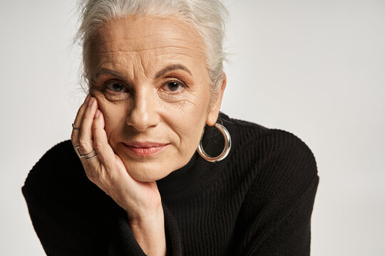 business portrait, middle aged business woman in turtleneck looking at camera on grey backdrop
