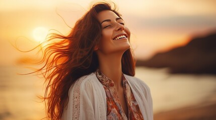 Portrait of calm happy smiling free woman with open arms and closed eyes enjoys a beautiful moment life on the seashore at sunset time - obrazy, fototapety, plakaty