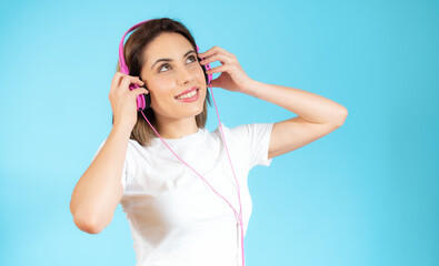 Young happy woman wear light shirt casual clothes yellow headphones listen to music dance look aside on area isolated on plaint pastel blue background studio portrait. Lifestyle concept
