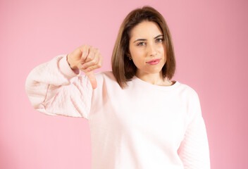 Woman, hand and thumbs down to disagree, failure or disapproval against a white studio background. Portrait of a isolated female pointing thumb down for incorrect, wrong or fail on pink background