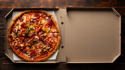 Pepperoni pizza with bell peppers sweetcorn and arugula in open carton box on dark wooden table...
