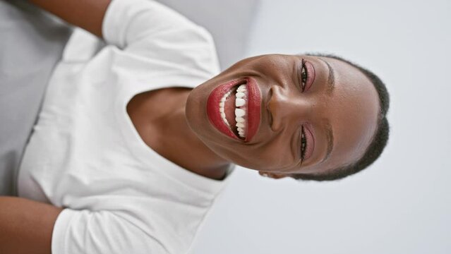 Attractive african american woman lying on her comfy bedroom bed, puffing cheeks in amusing expression, making a crazy funny face, mouth filled with air