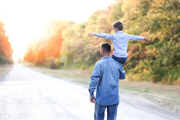 A Happy parent with a child in the park hands on nature travel go along the road
