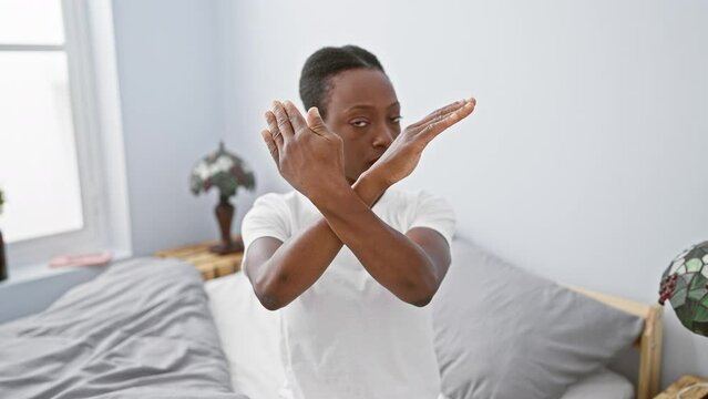 Fuming african american woman in bedroom, comfortably lying on bed, displaying a clear sign of rejection by crossing her arms - a raw portrait of negative emotions at home.