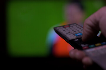 Hand with television remote control changing television channels horizontally soccer
