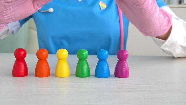 LGBT pride month health protection safety concept. Doctor with rainbow figurines of people from lesbian, gay bisexual, transgender, homosexual and pansexual community