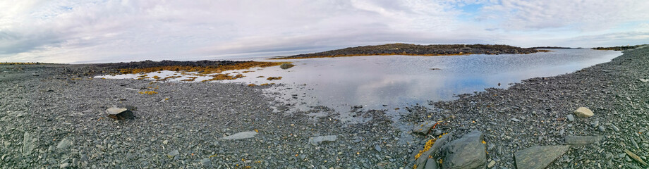 The rocky coast of the Barents Sea. Beautiful view of the rocks and the coast of the Rybachy and Sredny peninsulas, Murmansk region, Russia. The landscape is the harsh beauty of the north.
