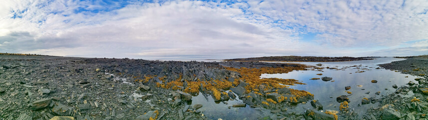 The rocky coast of the Barents Sea. Beautiful view of the rocks and the coast of the Rybachy and Sredny peninsulas, Murmansk region, Russia. The landscape is the harsh beauty of the north.