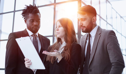 Portrait of three people in business wear discussing document in office.