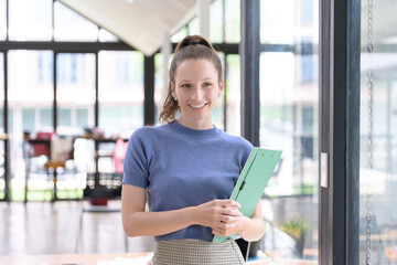 Beautiful and smiling businesswoman with paperwork in her hands standing in the office.