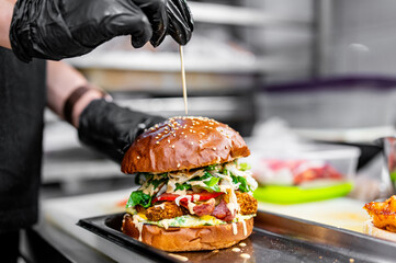 chef hand cooking cheese burger with vegetables and meat on restaurant kitchen