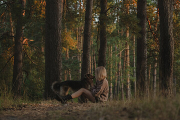 A young woman with her dog in a summer park. Happy girl walking in the woods with her mongrel dog....