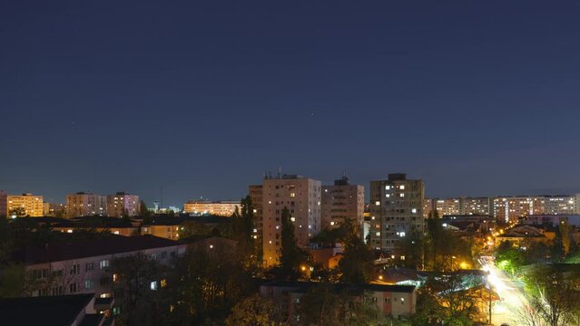 Day to night timelapse of Eastern Europe apartment buildings and city lights, with sunset clouds clearing for a black night sky.