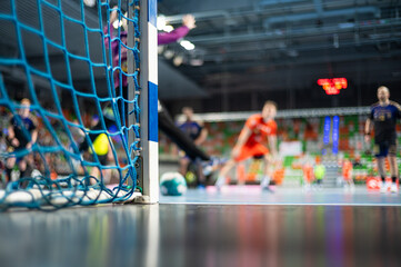 Detail of handball goal post with net and handball match in the background. - obrazy, fototapety, plakaty