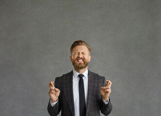 Please, make it happen. Funny cheerful businessman hoping for the best. Studio portrait happy man in business suit keeping fingers crossed, believing in luck and asking god to make his wish come true
