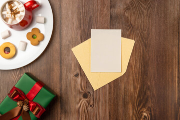 Envelope with card on table with Christmas gifts and mug of chocolate